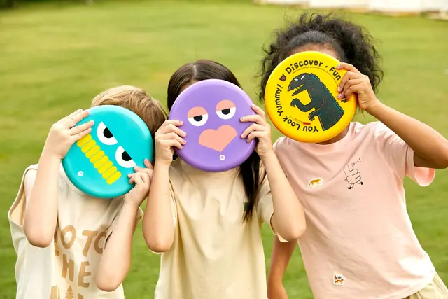 Children holding mideer frisbees in a garden