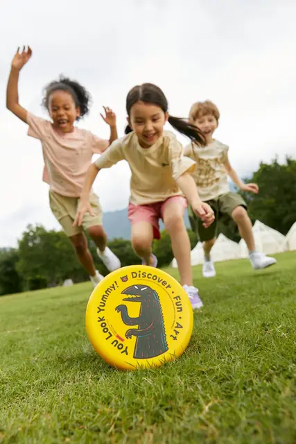 Children racing across the grass with mideer toys