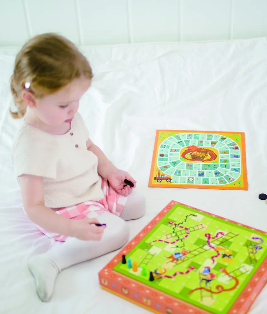 A young girl playing a mideer board game on a bed